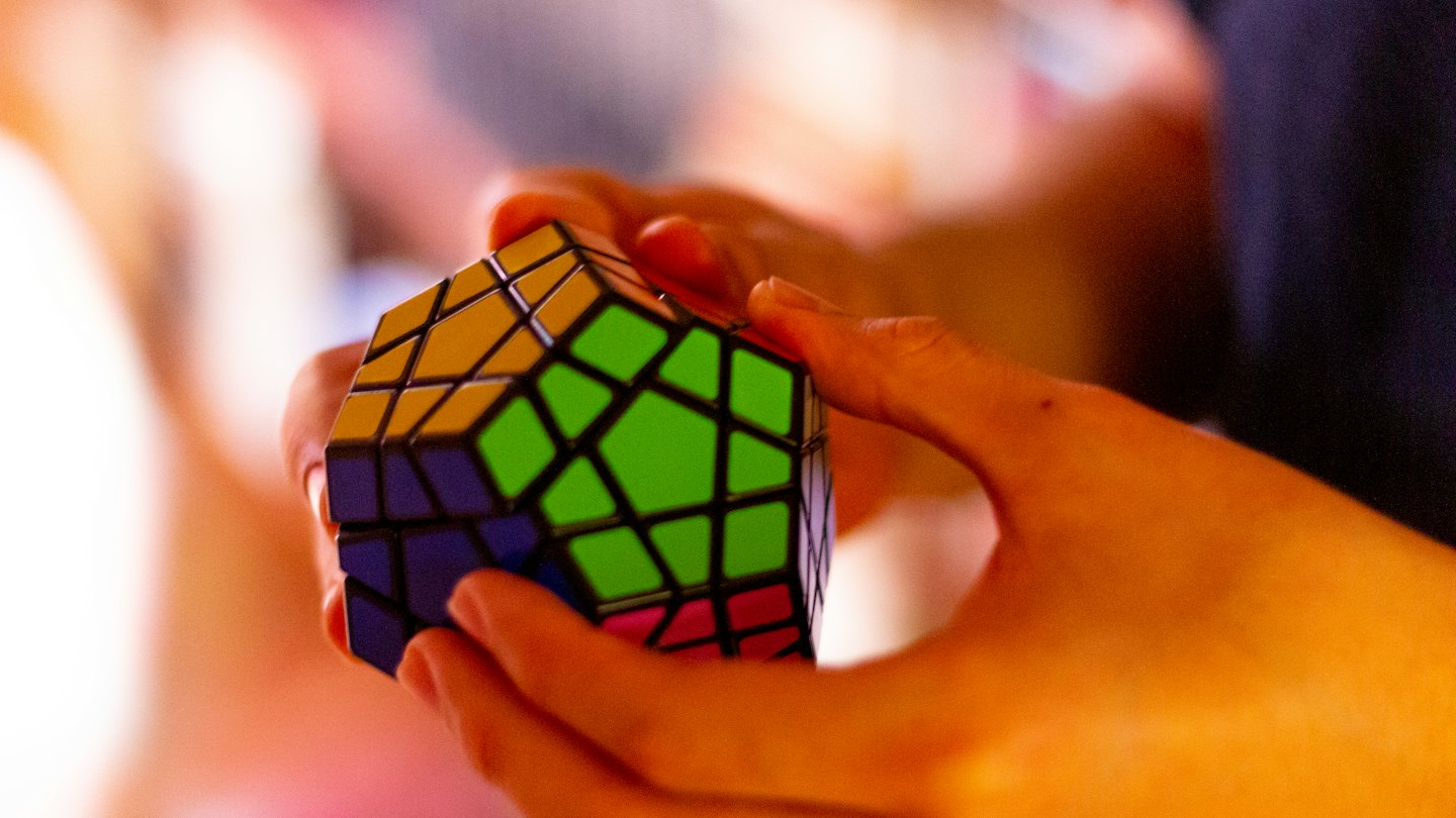 Manos resolviendo un cubo de rompecabezas de colores.