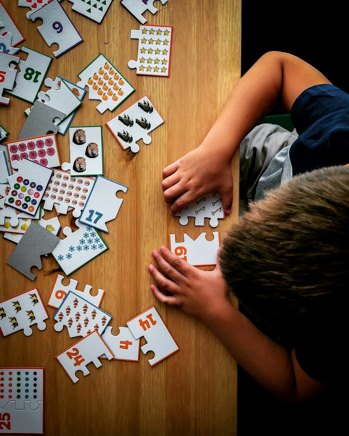 Niño jugando con rompecabezas educativos de números sobre una mesa de madera.