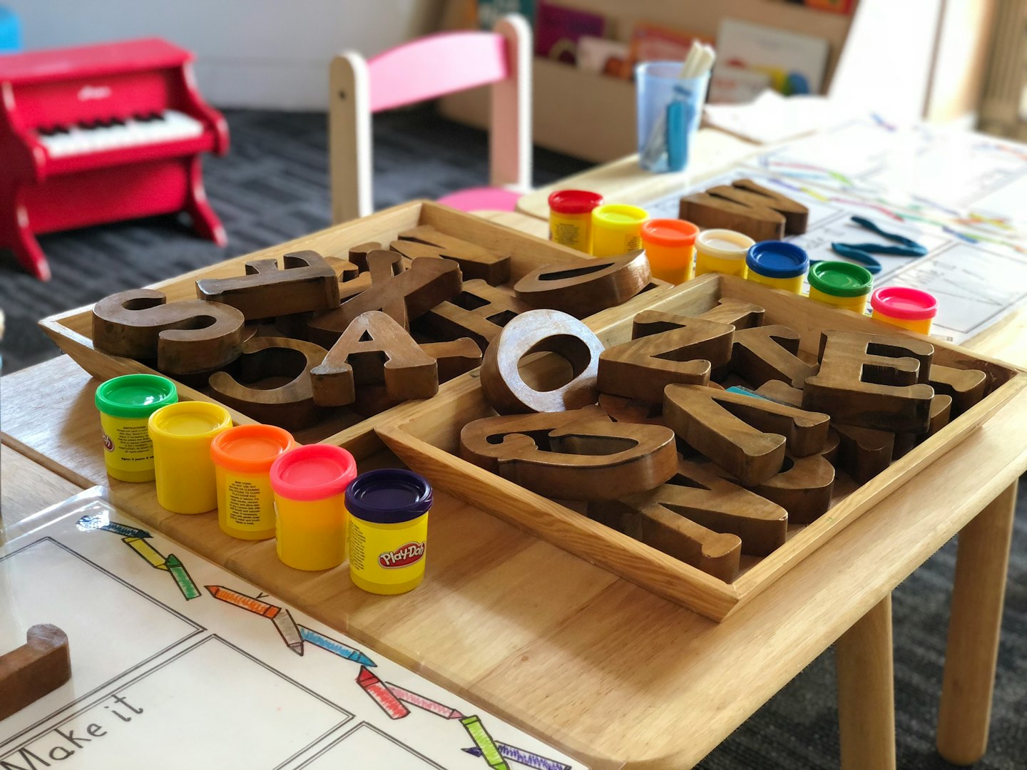 Mesa de actividades infantiles con bloques de letras y plastilina.